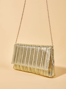 Dettaglio della trama plissettata dorata e tracolla a catena sulla borsa da sera clutch