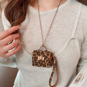 Detail of leopard print leather mini bag necklace with gold clasp on white knit sweater