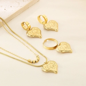 Detailed view of 18K gold plated hammered heart jewelry set on premium stone and silk background
