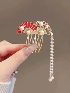 Detailed shot of golden magnolia hair comb with red enamel fans and pearl tassels