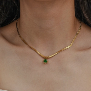 Close-up of golden snake chain necklace with a round green gemstone pendant