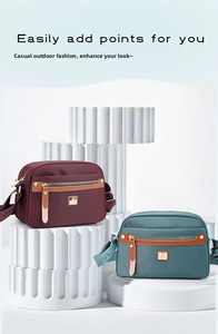 Detail of multi-pocket nylon crossbody bags in burgundy and grey-blue with metal logo