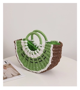 Dettaglio di una borsa in paglia a forma di anguria con fodera verde e doppi manici