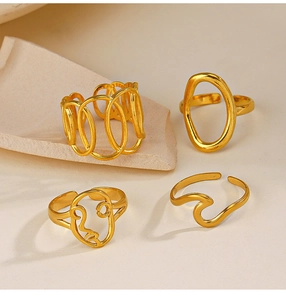Detail of four gold adjustable stainless steel rings with abstract faces and geometry