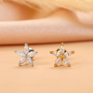 Close-up of gold and silver flower star cartilage studs with clear cubic zirconia