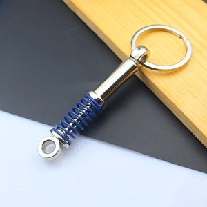 Detailed view of silver metal shock absorber keychain with blue spring on wood
