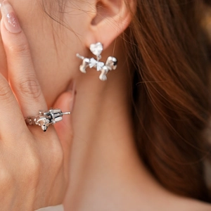 Close-up of silver poodle stud earrings with heart stones and a matching ring set