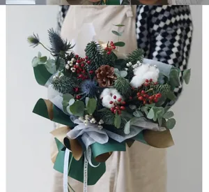 Close-up of Christmas bouquet with pine branches, cotton and red berries in green wrap
