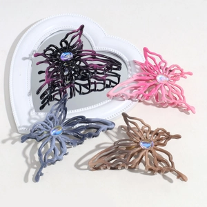 Detail of four butterfly hair claws with hollow design and gradient crystals on a heart mirror
