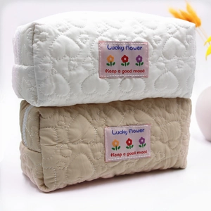 Quilted heart cosmetic bags in white and beige featuring colorful floral Lucky Flower patches