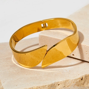 Macro view of gold wide cuff bracelet showing the spring hinge and mirror finish texture
