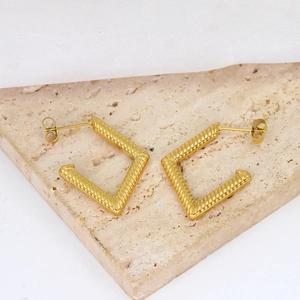 Detailed view of gold geometric V-shaped earrings with textured twisted metal surface