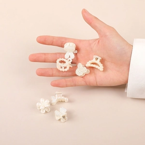 Mini pearl hair clips set with flower and butterfly shapes on soft pink background