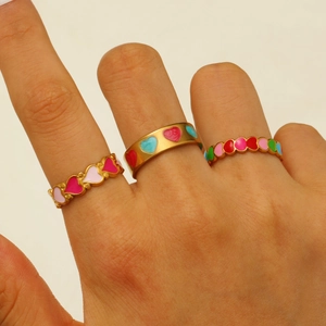 Detail of gold-plated geometric rings set featuring colorful enamel heart patterns