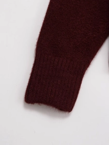Macro shot of ribbed cuffs on burgundy knit sweater showing soft textured fabric