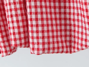 Macro view of red and white gingham fabric with textured seersucker finish and stitching
