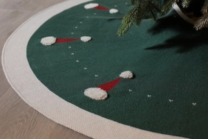 Détail du tapis de sapin de Noël en tricot vert foncé avec bonnets rouges en 3D