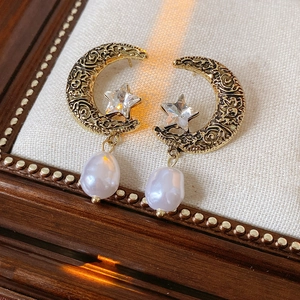 Detail of vintage gold crescent moon earrings with star crystal and baroque pearl pendant