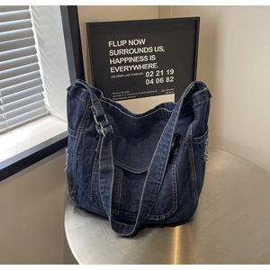 Détail du sac cabas en denim bleu foncé avec boucle réglable et bords délavés rétro