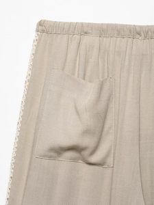 Detail of elastic waistband and beige cotton-linen fabric with white crochet side lace