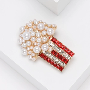 Macro detail of popcorn brooch featuring white pearls and red rhinestone stripes
