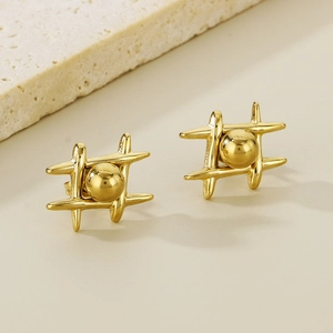 Polished gold stainless steel cross geometric earrings with center bead on beige surface