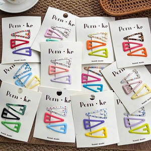 Close-up of colorful triangle hair clips with floral and plaid patterns on cards