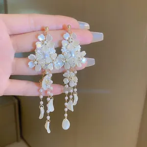Gros plan détaillé de boucles d'oreilles à pompon avec pétales de perles et strass