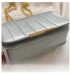 Detail of silver quilted crossbody bag with gold chain strap and metallic finish