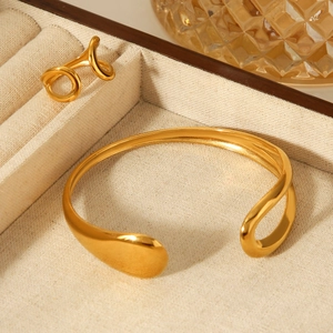 Minimalist gold teardrop bangle and ring set on beige linen jewelry display case