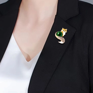 Vintage gold fox brooch with large green gemstone and sparkling crystals on blazer