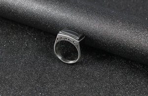 Detail of men's stainless steel signet ring with black zircon and hollow geometric carving