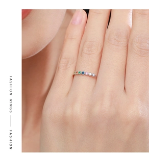 Gros plan d'une bague en argent 925 avec sept pierres arc-en-ciel sur le doigt