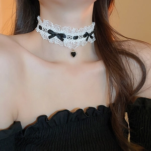 Close-up of white lace choker featuring a black ribbon bow and heart pendant on model