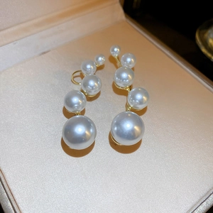 Detailed view of white pearls in graduated sizes set in a gold-plated curved earring
