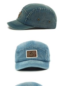Λεπτομέρεια καπέλου 5-panel από ξεπλυμένο denim με καφέ επίθεμα και μεταλλικό κρίκο
