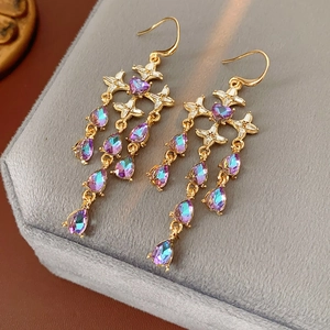 Close-up of vintage gold tassel earring with cross motif and blue crystal pendant