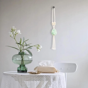 Detail of handmade woven cotton wall hanging with natural green raw stone and wooden beads