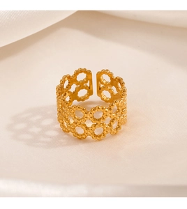 Detail of adjustable gold ring with geometric cutouts and beaded edges on white silk