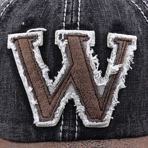 Detail of vintage denim baseball cap featuring a fuzzy brown W patch with frayed edges