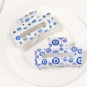 Pearlescent white Evil Eye hair claw clip with star and moon motifs on a ceramic plate