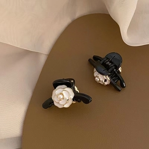 Detail shot of a pair of black claw clips with white camellia and pearl embellishments