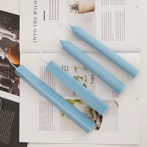 Blue geometric scented candles in striped and smooth pillar shapes on a magazine