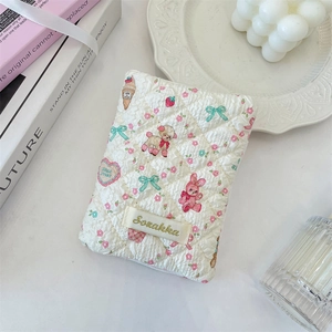 Detail of cream quilted passport organizer with cute cartoon bunny and sheep patterns