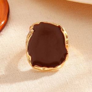Macro detail of vintage irregular gold ring with smooth dark brown enamel inlay