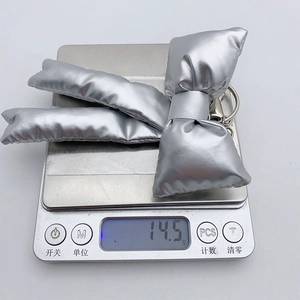 Macro detail of silver padded bow keychain weighing 14.5g on a digital scale