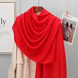 Detail of red linen-cotton scarf with smooth texture draped over a beige trench coat
