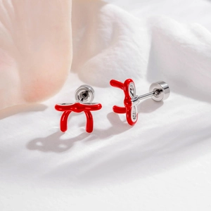 Minimalistische rote Schleifen-Ohrstecker mit Emaille-Finish auf weißem Stoff
