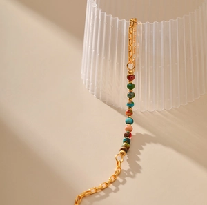 Macro detail of gold 18K plated chain bracelet with colorful marble textured stone beads