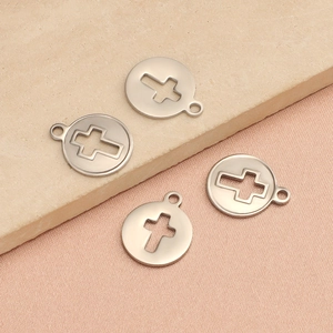 Vue détaillée de quatre pendentifs ronds en acier argenté avec motifs de croix évidés
